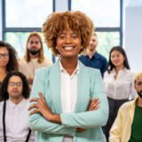 a confident and respected female being a leader while standing in front of a business team